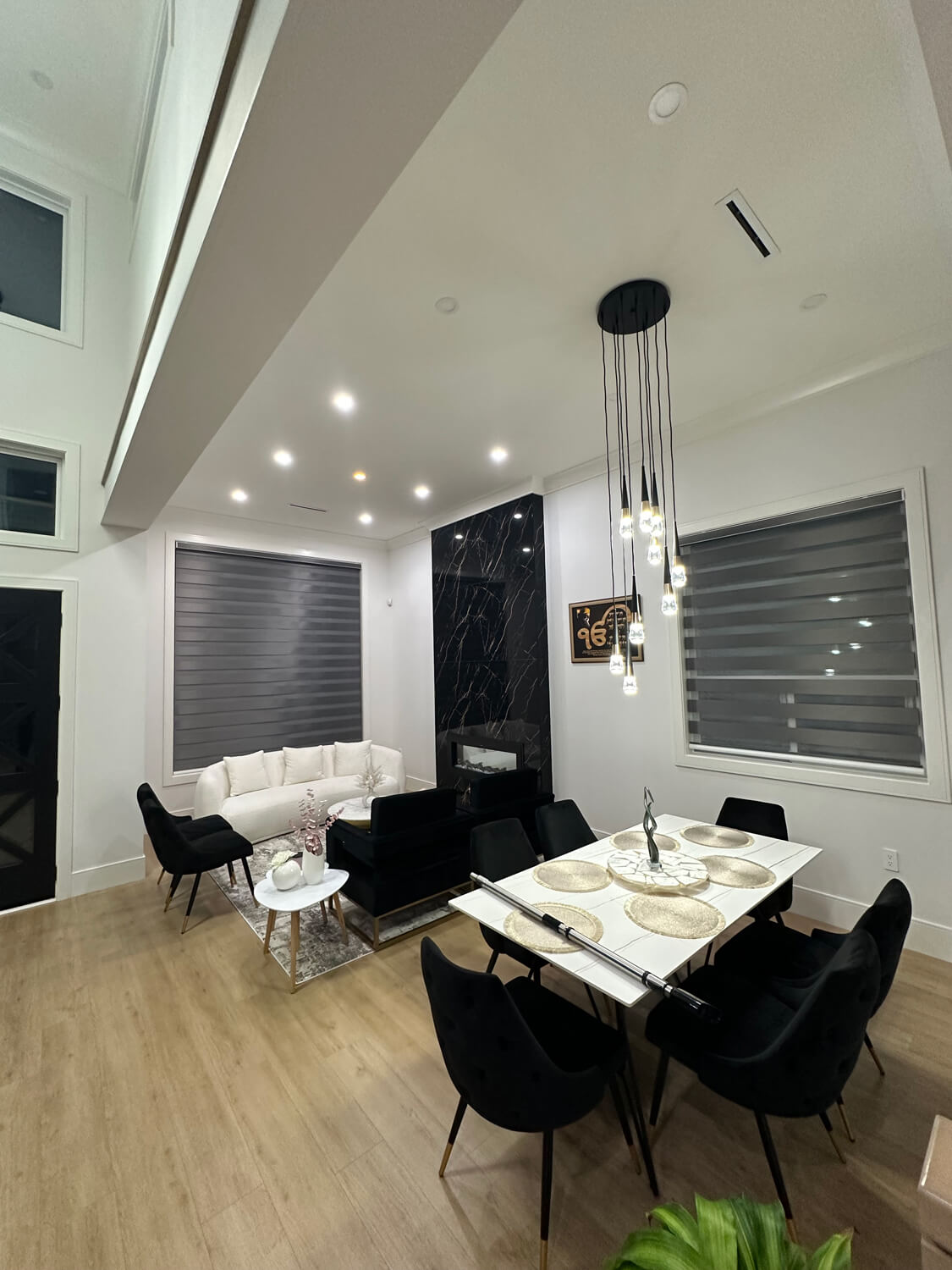 Modern open-concept dining and living area with high ceilings and wood-style flooring.